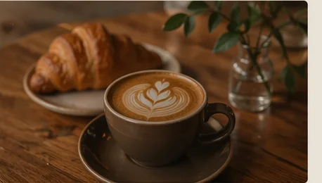 latte art coffee with croissant in a warm cafe setting
